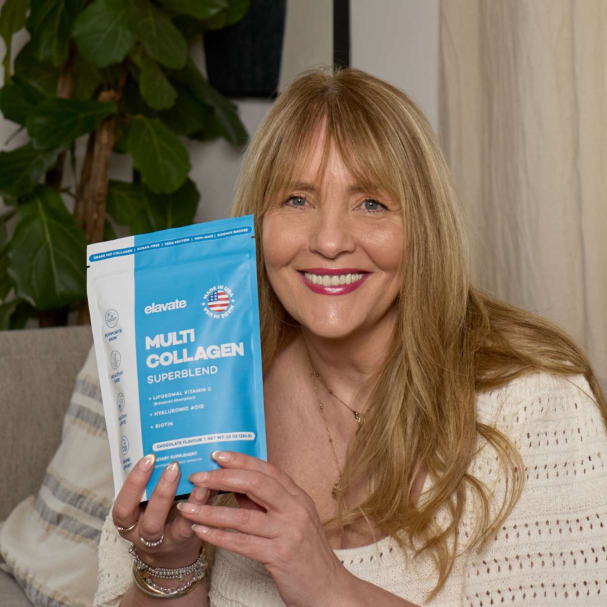 Smiling woman holding an Elavate Multi Collagen Superblend pouch labeled "MULTI COLLAGEN SUPERBLEND" and "Made in USA".